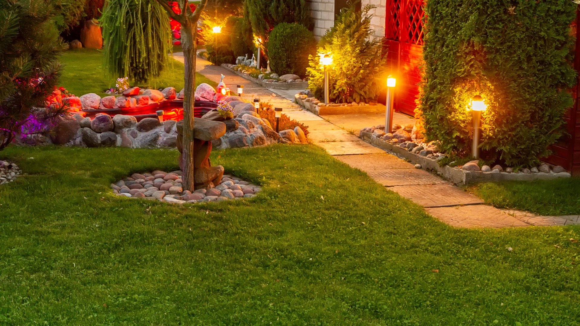 Our client's backyard and walkway in Mapleton, MN lit up in the evening after our landscape lighting installation. 