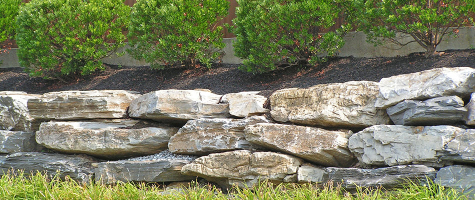 Boulder retaining wall built by landscape bed in Mankato, MN.