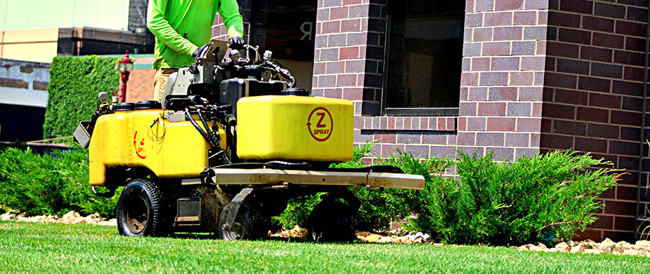 Professional on weed control sprayer applying treatment to lawn in Mankato, MN.