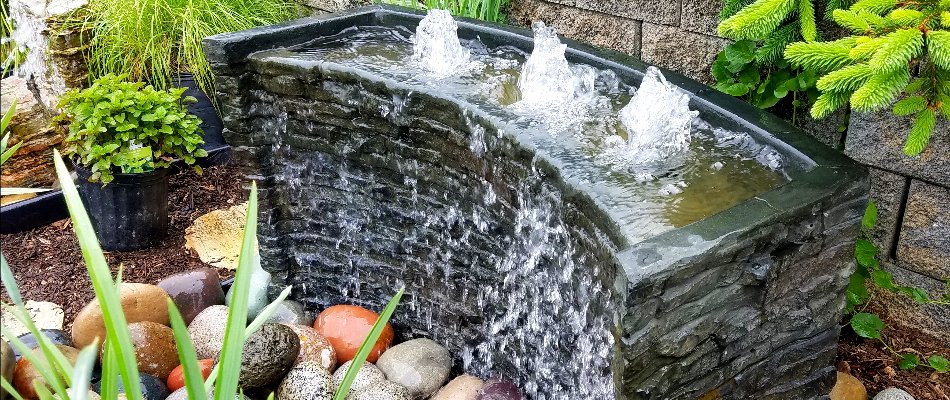 A grey stone bubbler water feature installed by our team on a property in Elysian, MN.