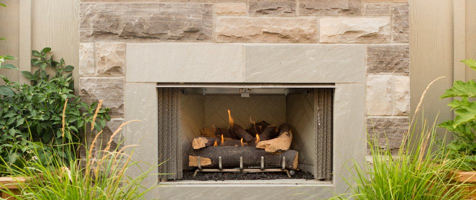 A neutral colored stone outdoor fireplace installed by our team for a client in Mapleton, MN.