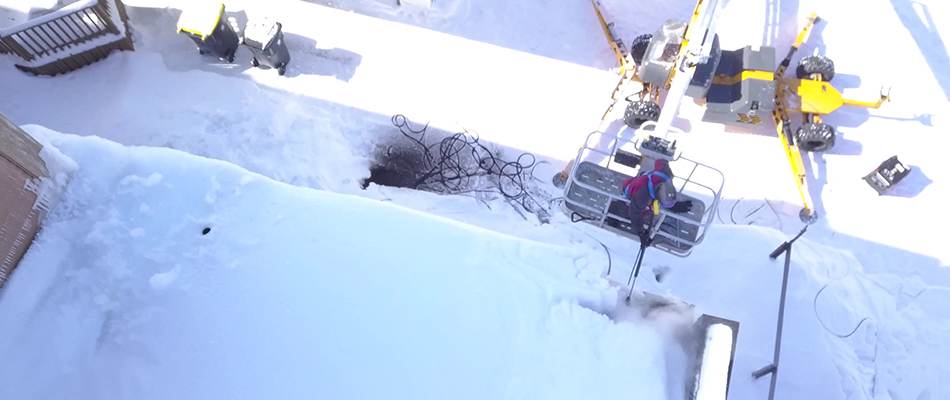Worker on an equipment to remove ice dam in North Mankato, MN.